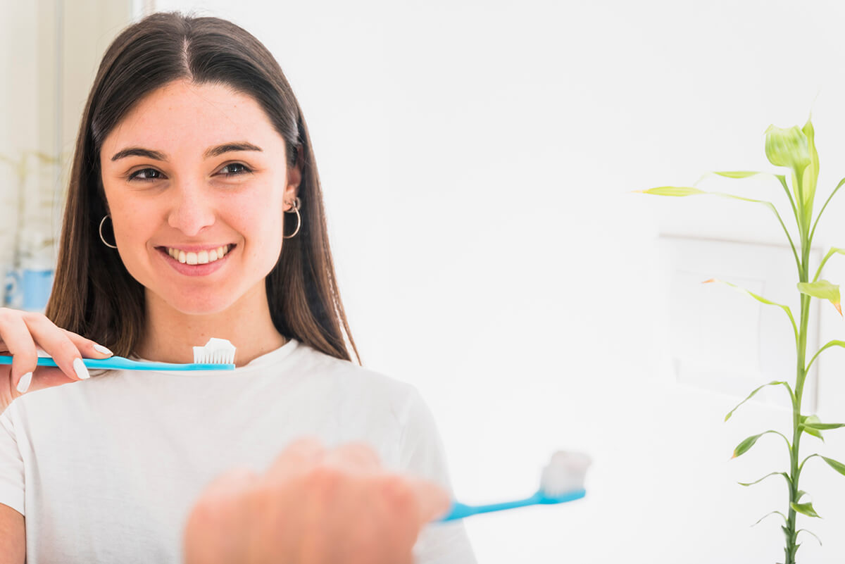Uśmiechnięta dziewczyna trzyma szczoteczkę do zębów - higiena ciała