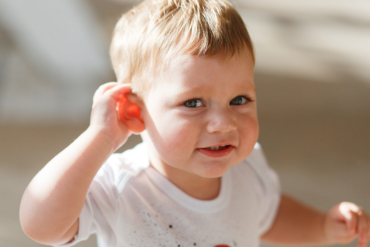 Mały chłopiec dotyka dłonią ucha.