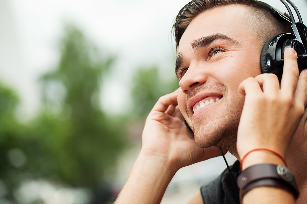 Mężczyzna słucha muzyki przez słuchawki - Czy słuchawki mogą uszkodzić słuch?