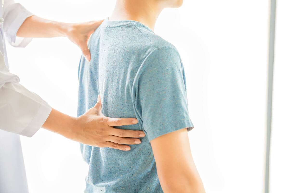 Lekarz bada pacjenta - O czym świadczy ból w kręgosłupie i kto może ci pomóc