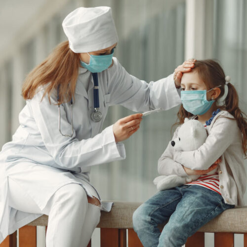 Lekarka mierzy temperaturę dziewczynce. Prywatna służba zdrowia podczas pandemii COVID-19