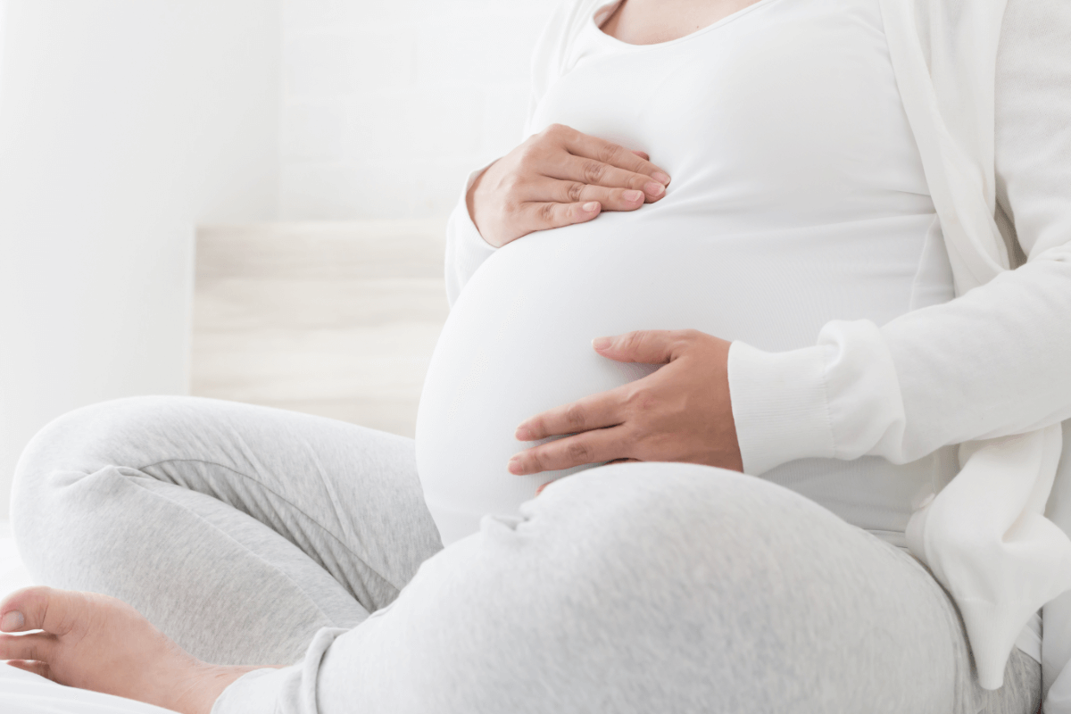 Kobieta w ciąży obejmująca brzuch. Nieregularna miesiączka po czterdziestce.