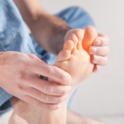 Mężczyzna trzymający się za stopę. Choroby stóp - o czym może świadczyć ból, swędzenie lub obrzęk?