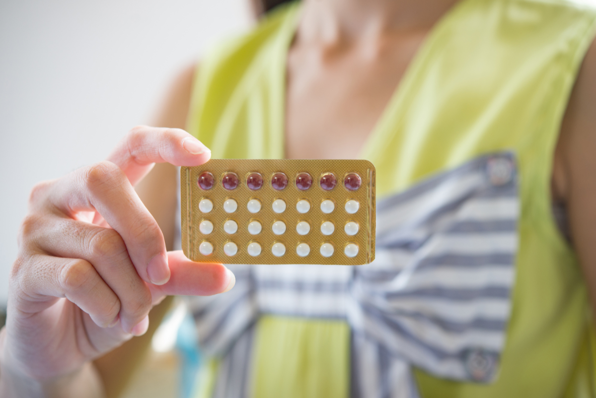Kobieta trzyma tabletki antykoncepcyjne. Nowoczesna ginekologia - w trosce o zdrowie kobiety