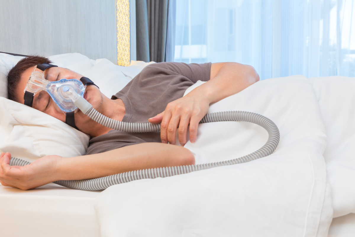 Leczenie bezdechu sennego. Mężczyzna śpiący w masce CPAP