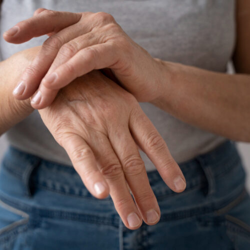 Kobieta trzyma się za bolący nadgarstek. Bóle w stawach — co może być przyczyną