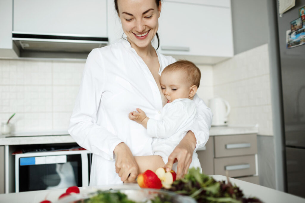 Matka z dzieckiem na ręku przygotowuje zdrowy posiłek