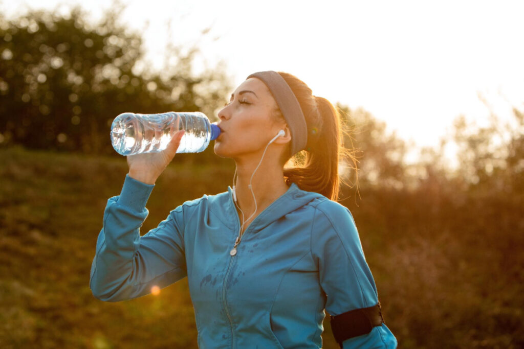 Kobieta pije wodę w trakcie biegania
