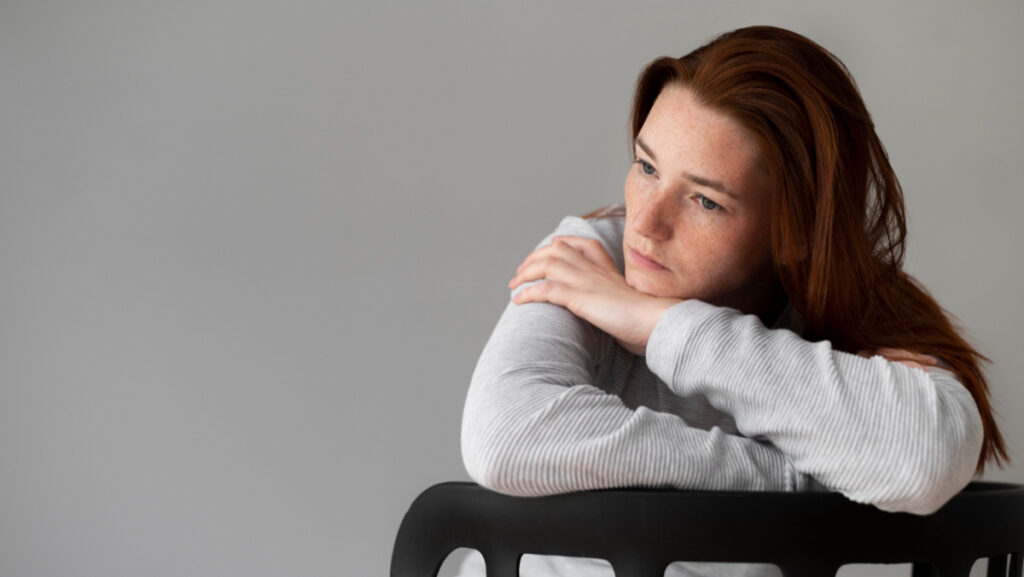 Przygnębiona kobieta na krześle - kiedy pomoc psychologiczna online ma sens
