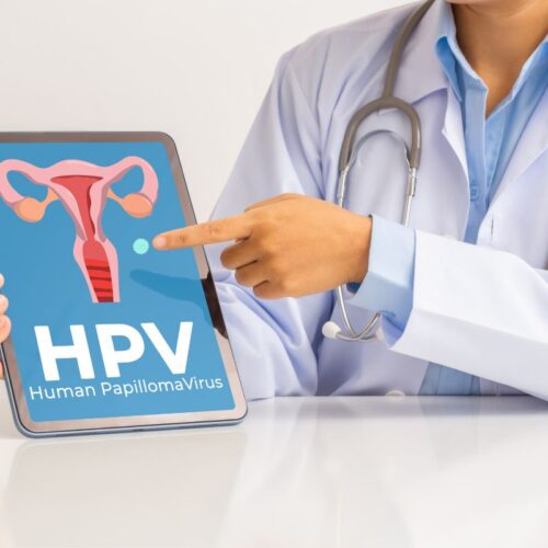Lekarka wskazuje na grafikę z macicą kobiety i napisem HPV - Wirus HPV - objawy, leczenie, zapobieganie