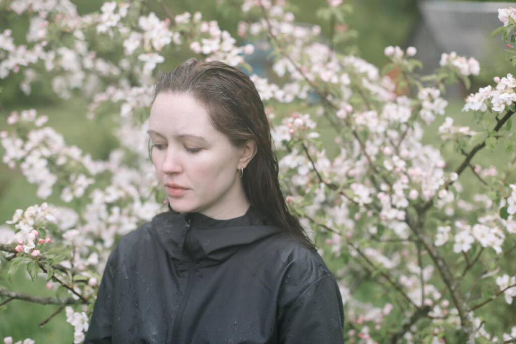 Smutna kobieta w ogrodzie z kwitnącymi drzewami - wiosenna depresja
