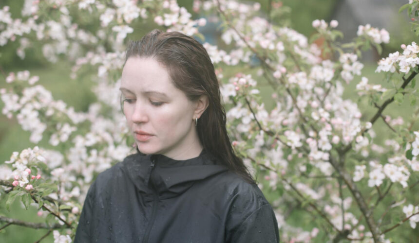 Smutna kobieta w ogrodzie z kwitnącymi drzewami - wiosenna depresja