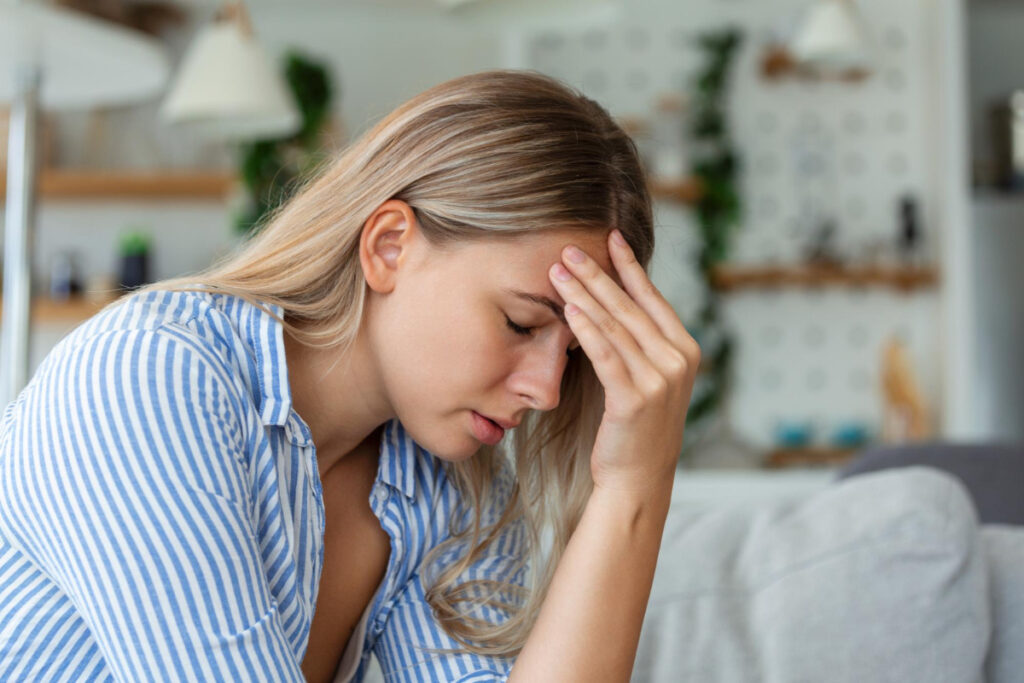 Kobieta trzymająca się za bolącą głowę - migrena - przyczyny jaskry i czynniki ryzyka