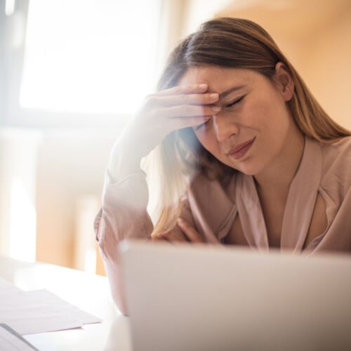 Kobieta z bólem głowy w pracy - Migrena – przyczyny, objawy i metody leczenia