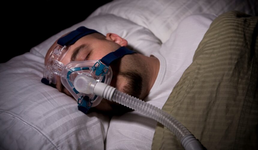 Mężczyzna śpi w masce CPAP. Obturacyjny bezdech senny — kto jest na niego narażony