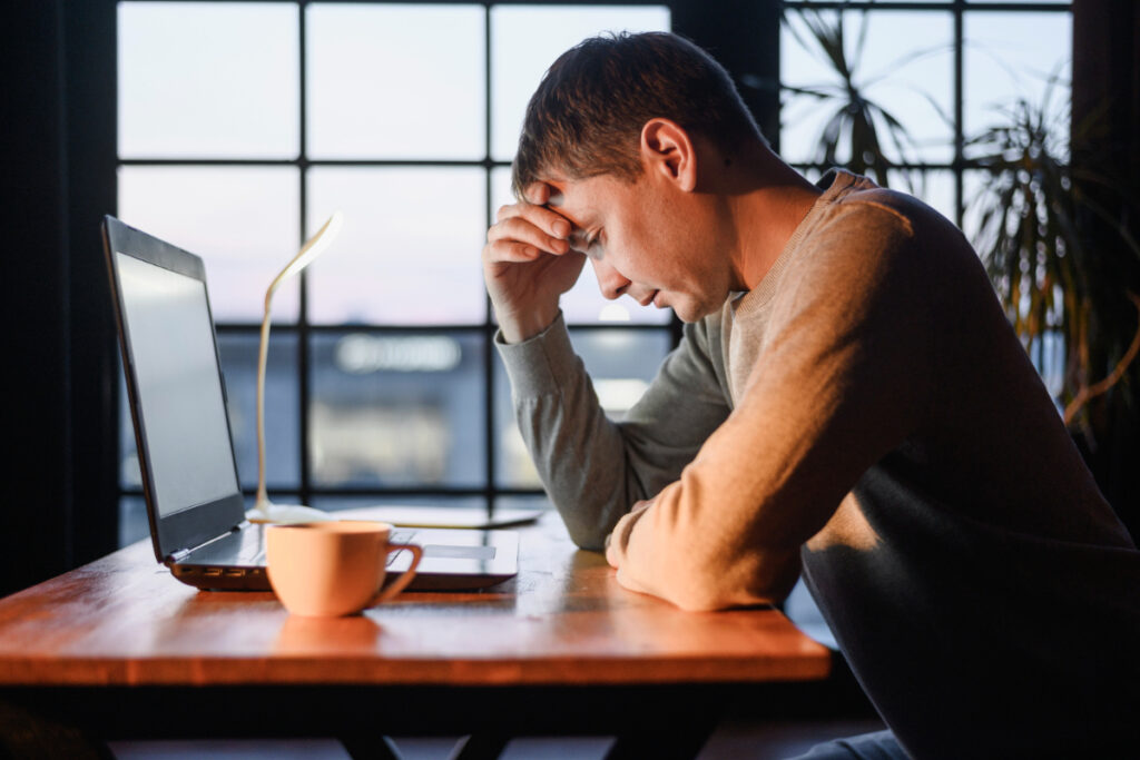 Zmęczona pracą kobieta przy laptopie . Wypalenie zawodowe