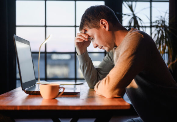 Zmęczona pracą kobieta przy laptopie . Wypalenie zawodowe